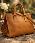 Dark Tan Faux leather handbag on a stone surface with a blurred floral background