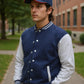 Man wearing a navy blue and white varsity jacket with a matching cap outdoors.