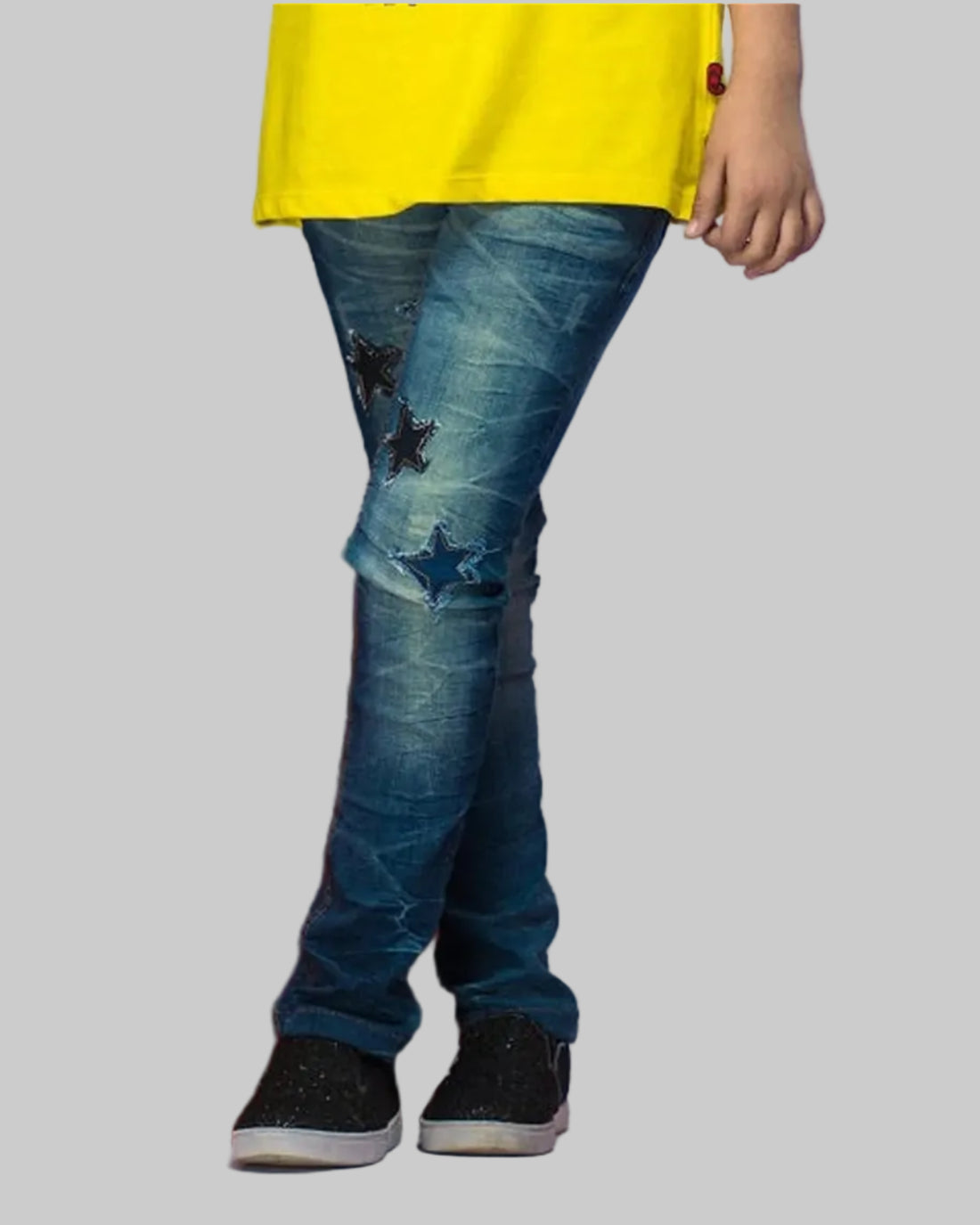 Person wearing blue jeans with star patterns and a yellow top, standing on red and gray blocks.