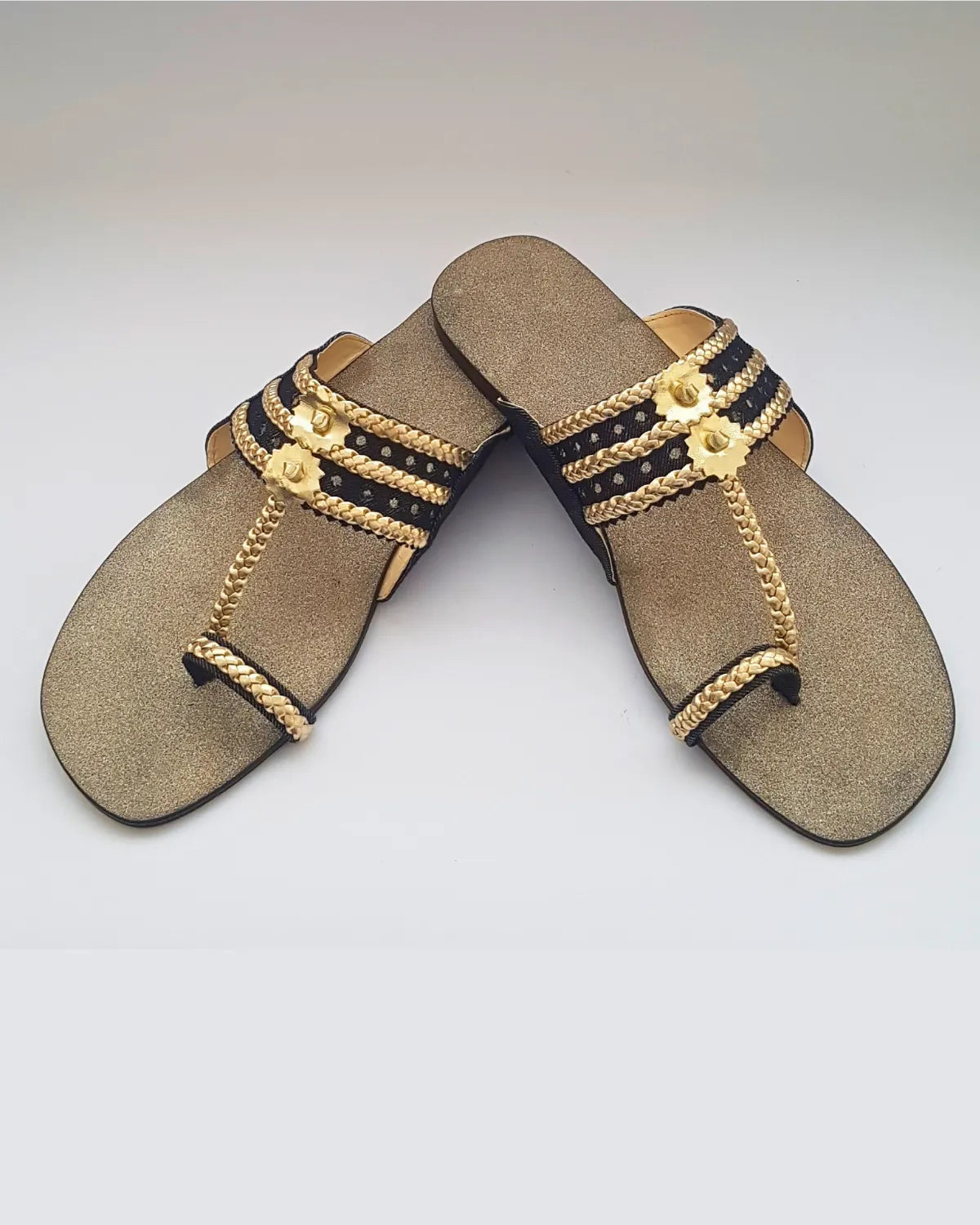 Pair of decorative sandals with gold and black accents on a white background