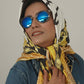 Person wearing a patterned scarf and sunglasses against a plain background