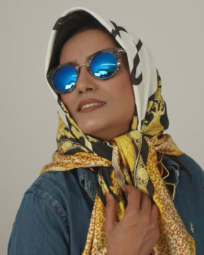 Person wearing a patterned scarf and sunglasses against a plain background