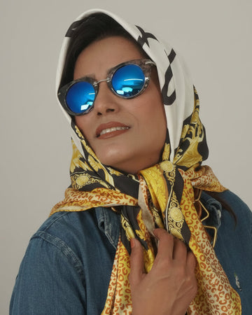 Person wearing a patterned scarf and sunglasses against a plain background