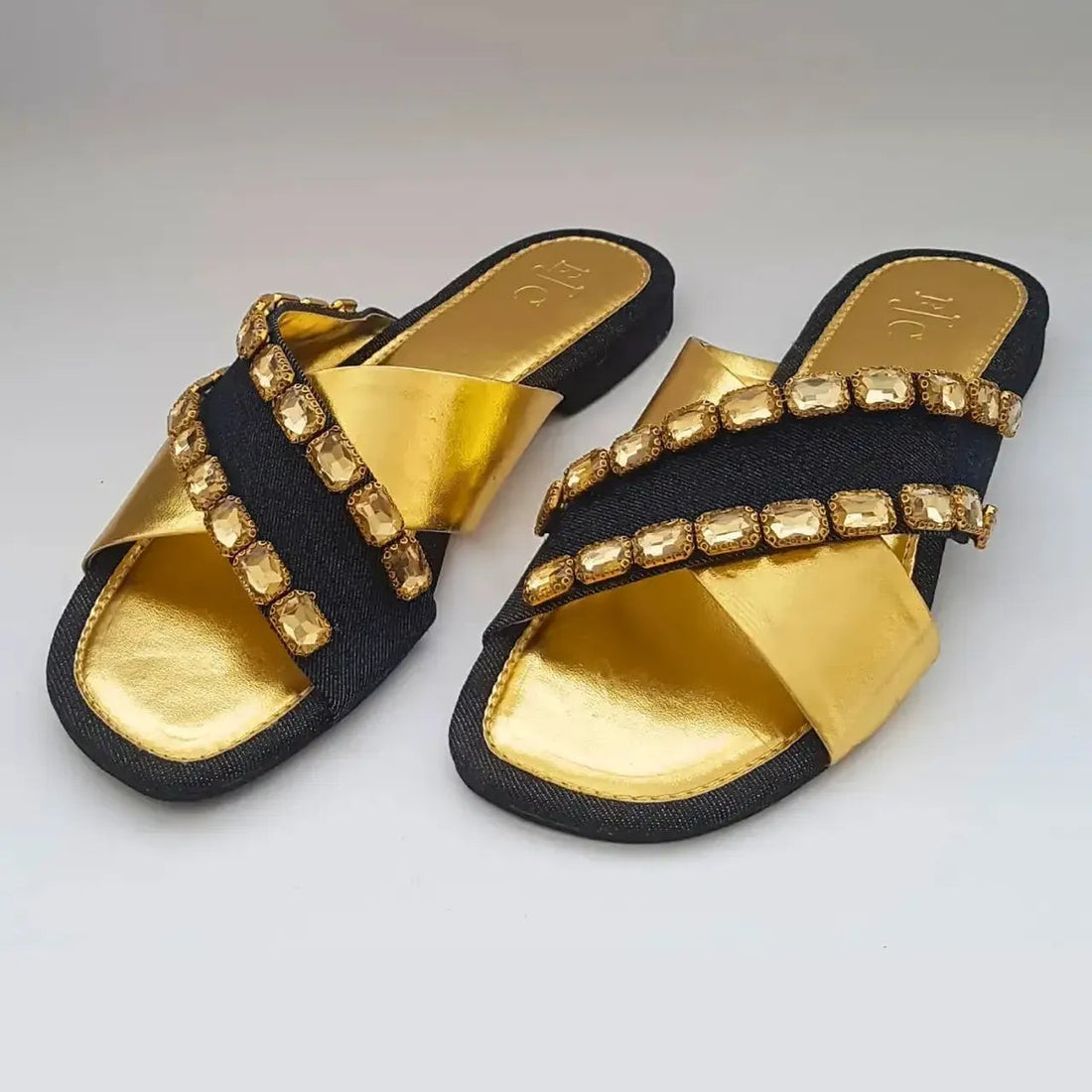Black and gold sandals with studded details on a light gray background