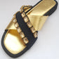 Black sandal with gold embellishments on a white background