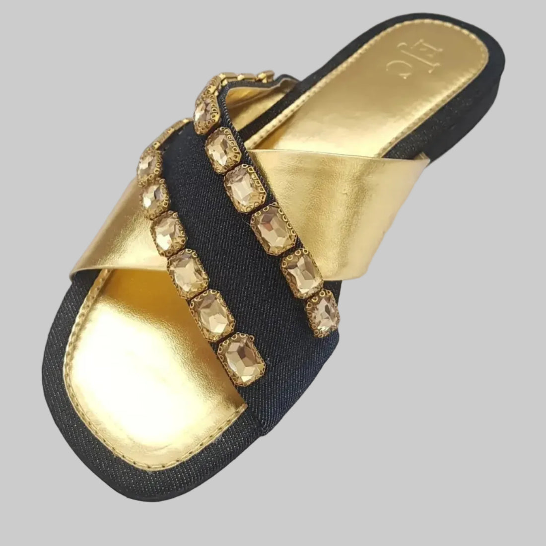 Black and gold sandals with studded details on a light gray background