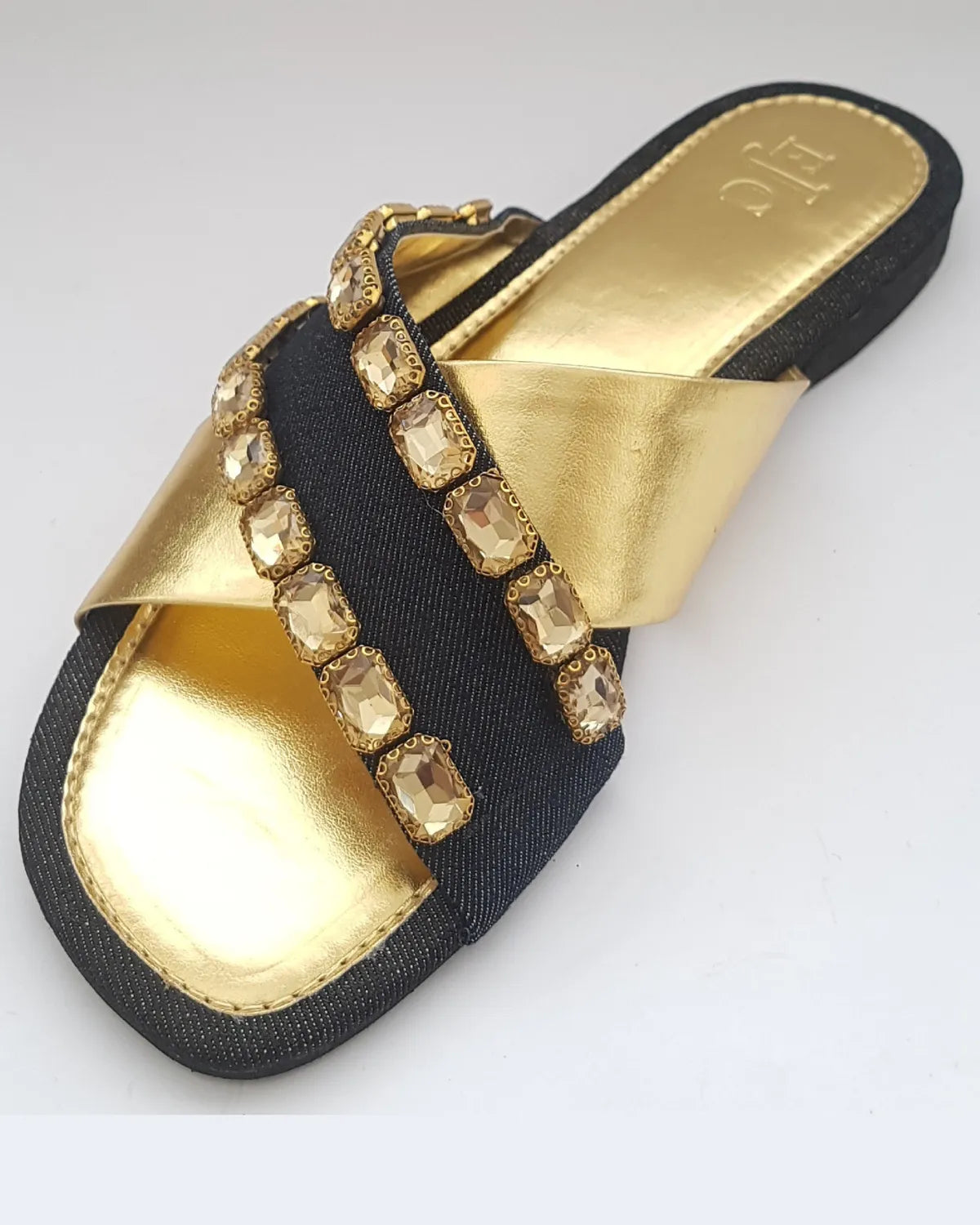 Black sandal with gold embellishments on a white background