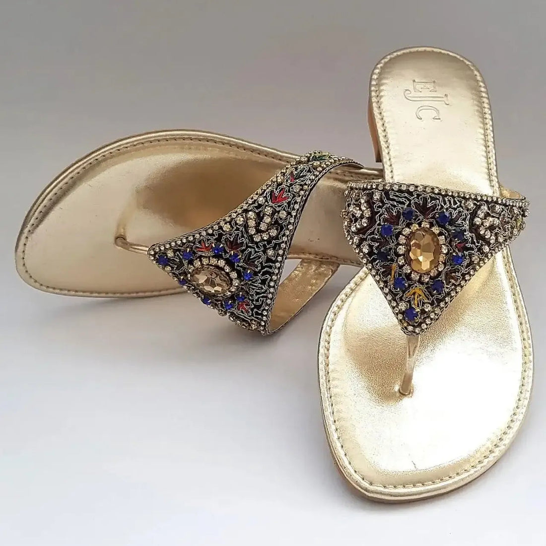 Gold sandals with decorative straps on a white background