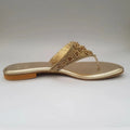 Gold sandal with embellishments on a light gray background