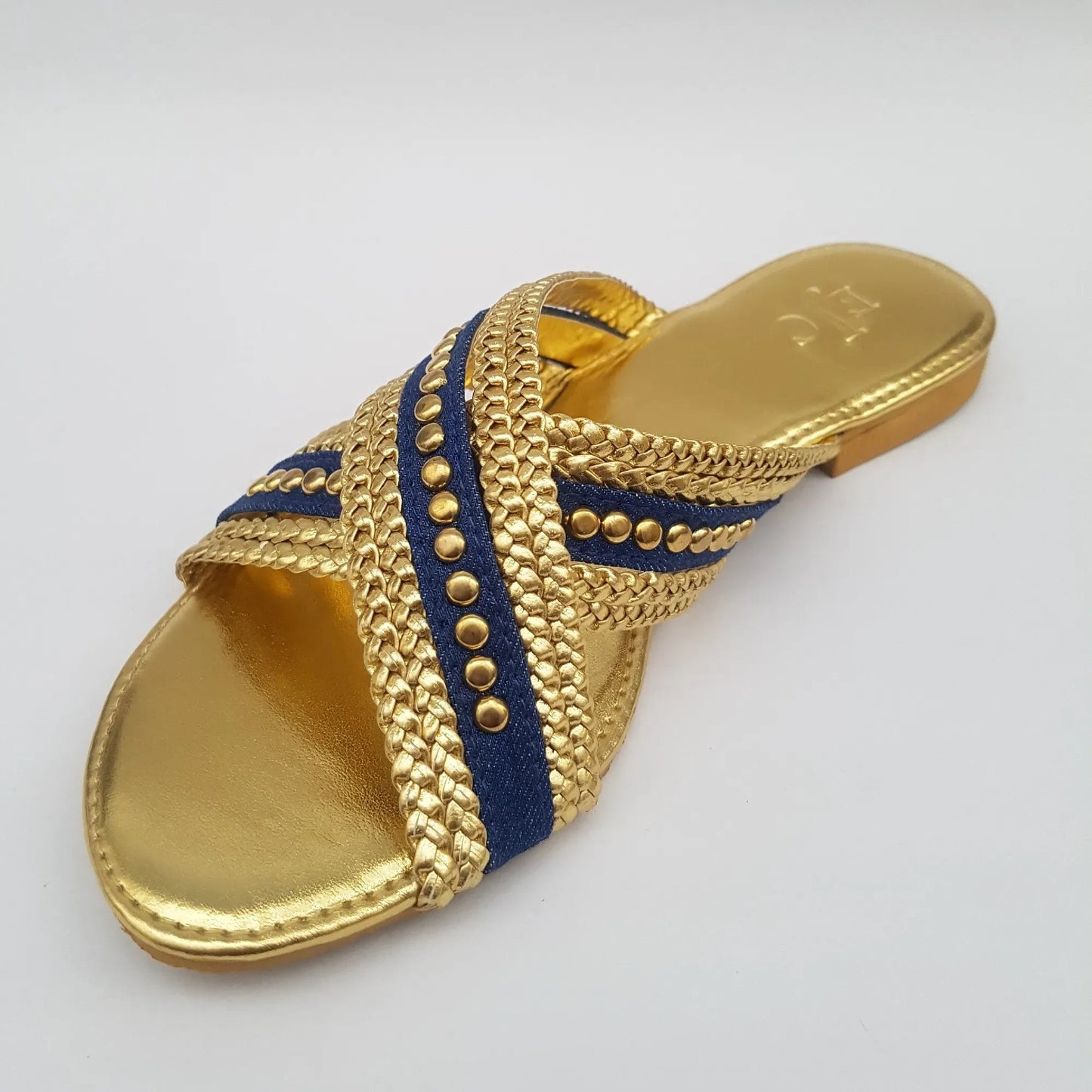 Gold sandal with blue accents on a light gray background