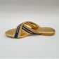 Gold sandal with blue accents on a light gray background