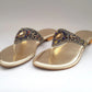 Gold sandals with decorative straps on a white background