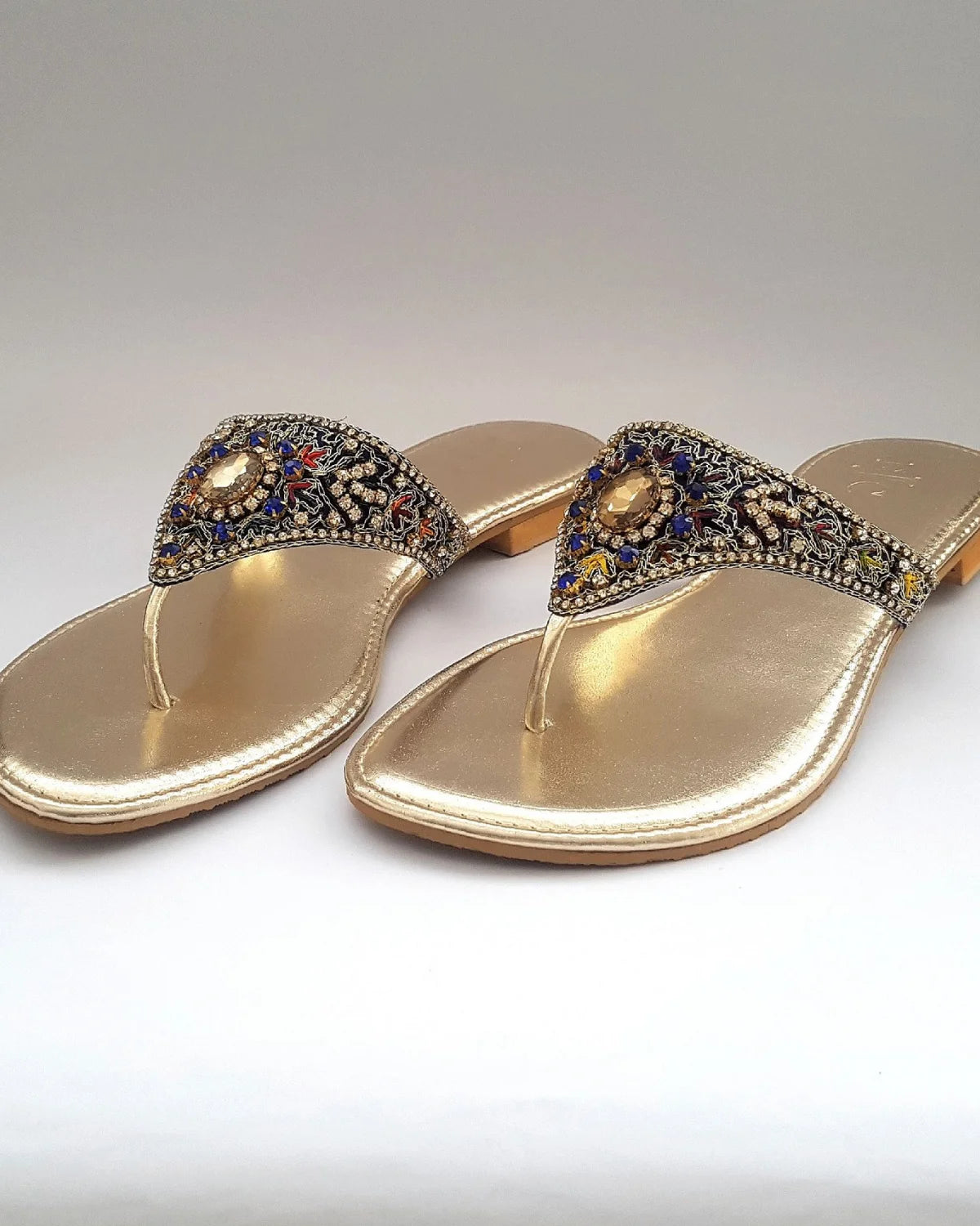 Gold sandals with decorative straps on a white background