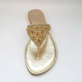 Gold sandal with embellishments on a light gray background