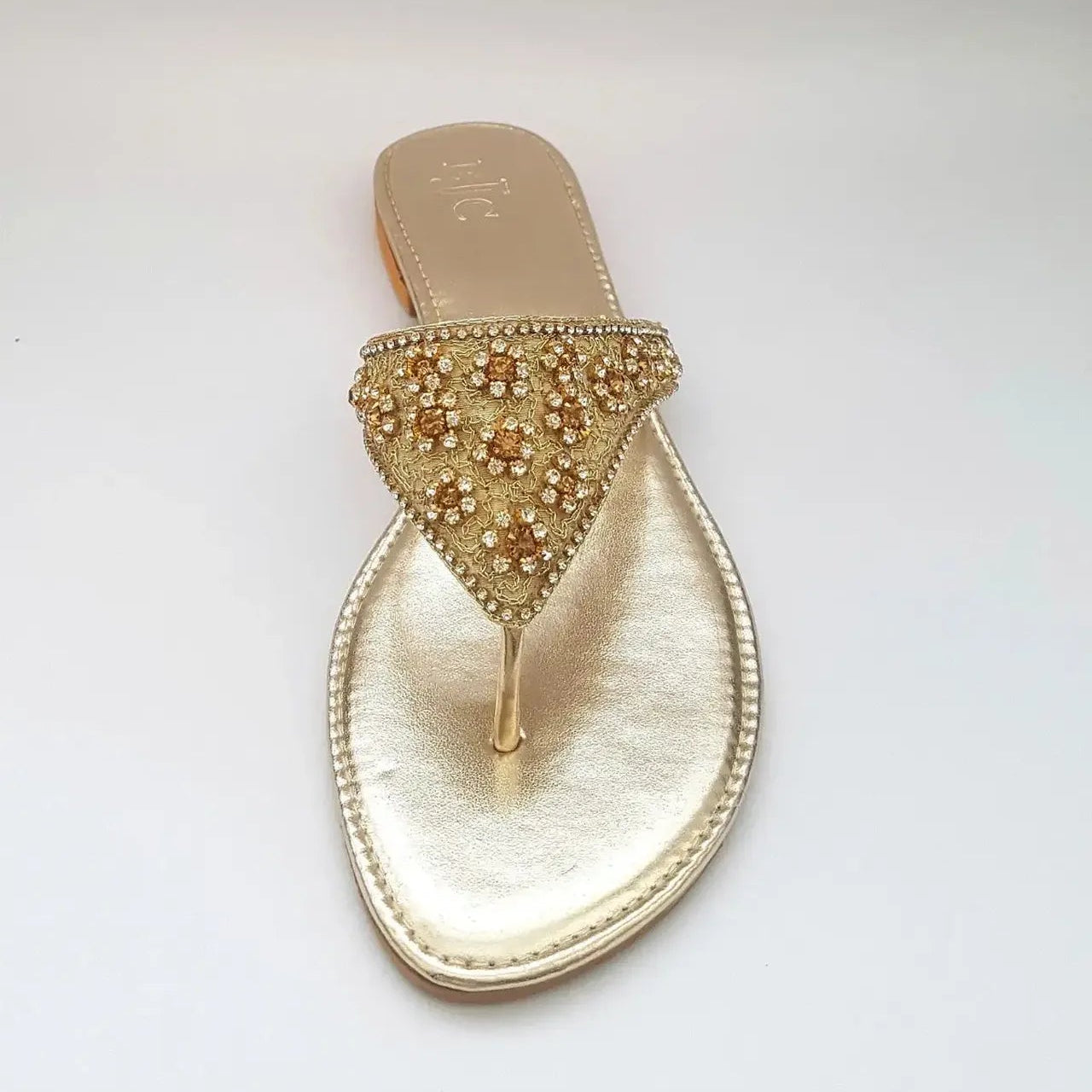 Gold sandal with embellishments on a light gray background