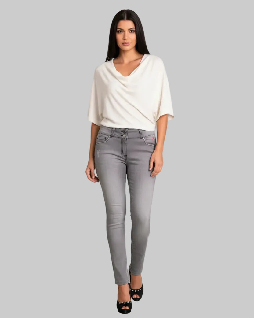 Woman wearing a white top and gray pants on a gray background