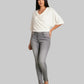 Woman wearing a white top and gray pants on a gray background
