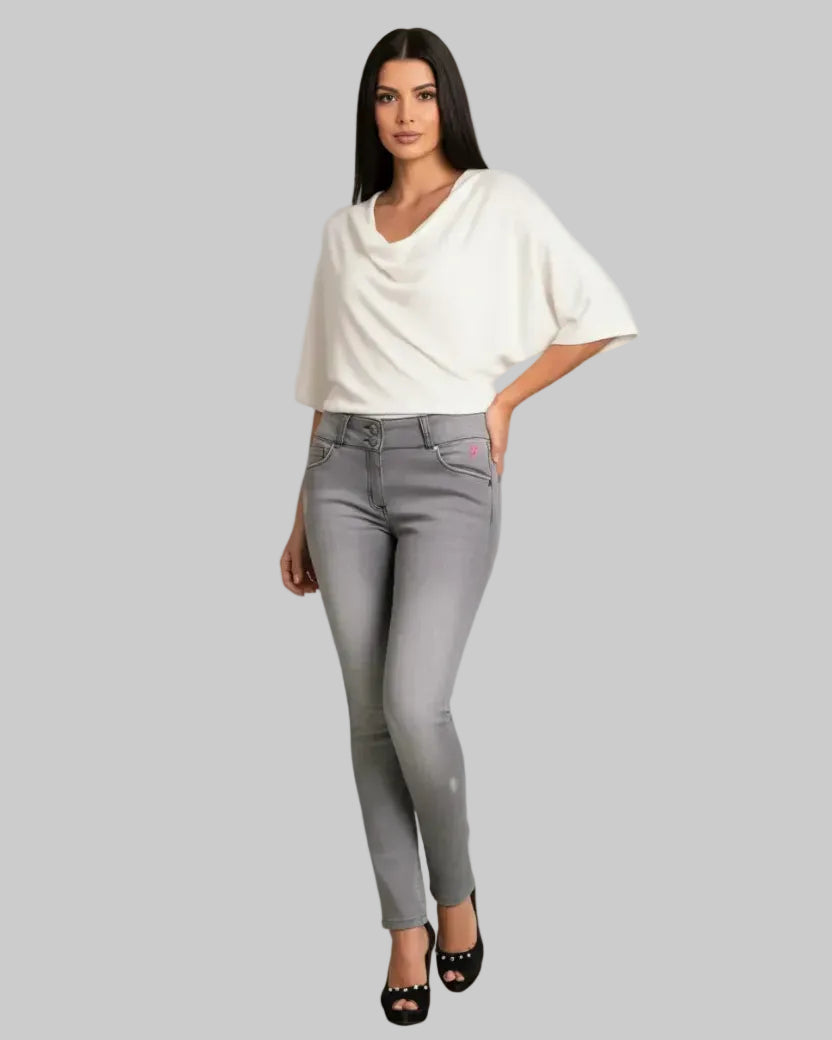 Woman wearing a white top and gray pants on a gray background