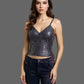 Woman wearing a sequined top and dark jeans against a neutral background