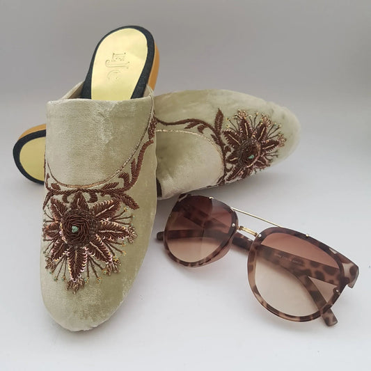 Decorative sandal with floral embroidery and sunglasses on a light gray background
