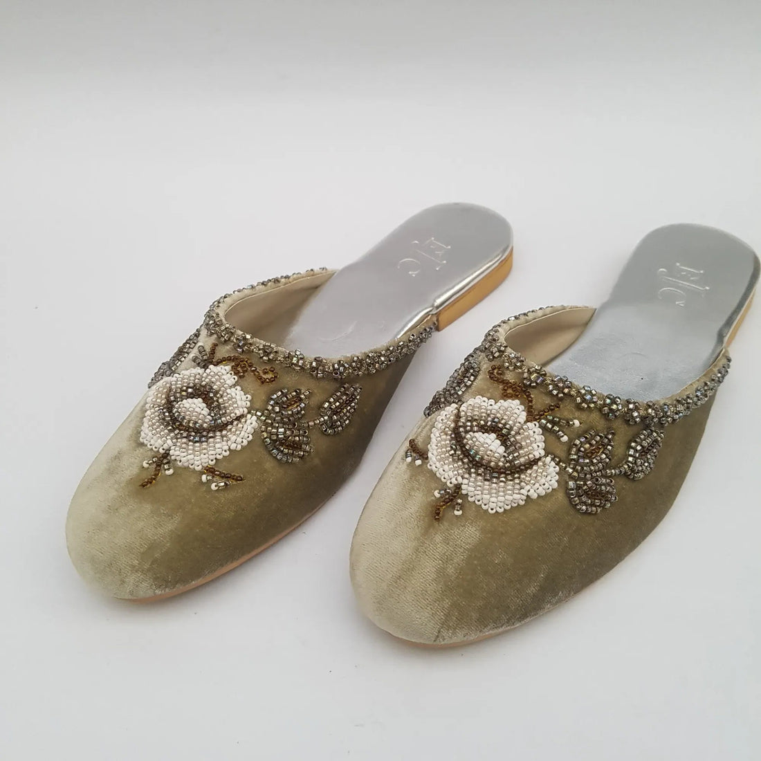 Pair of embellished shoes with floral designs on a light gray background
