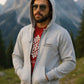 Man wearing a gray hoodie and sunglasses with mountains in the background