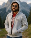 Man wearing a gray hoodie and sunglasses with mountains in the background