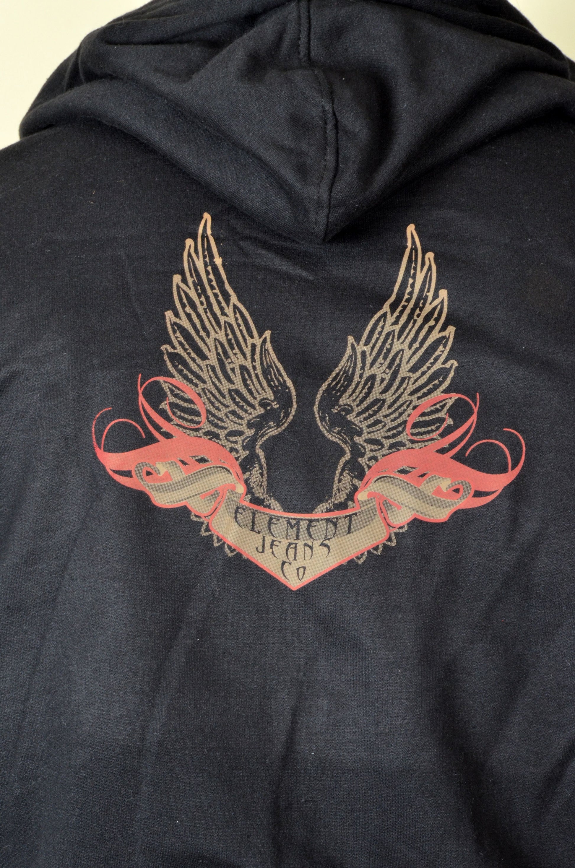 Black hoodie with winged logo and 'Element Jeans Co.' text on a beige background