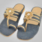 A pair of denim slippers embellished with stone embellishments and metallic trims.