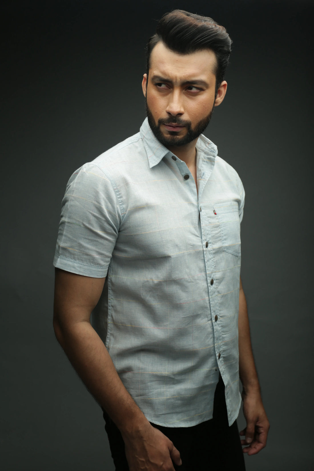 Man wearing a light gray button-up shirt against a dark background