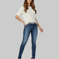 Woman wearing a white top and blue jeans on a gray background