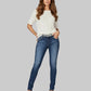 Woman wearing a white top and blue jeans on a gray background