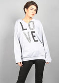 Person wearing a light gray sweatshirt with 'LOVE' printed on it against a plain background