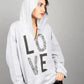 Person wearing a gray hoodie with 'LOVE' printed on it against a gray background