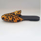 Leopard print slipper with a gold buckle on a white background