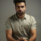 Man wearing a light olive shirt against a gray background