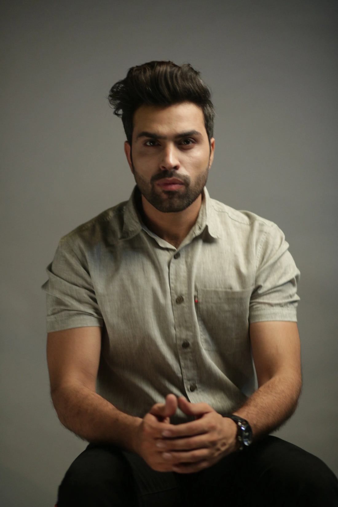 Man wearing a light olive shirt against a gray background