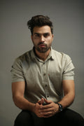 Man wearing a light olive shirt against a gray background