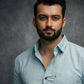 Man wearing a light blue shirt against a dark background