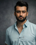 Man wearing a light blue shirt against a dark background