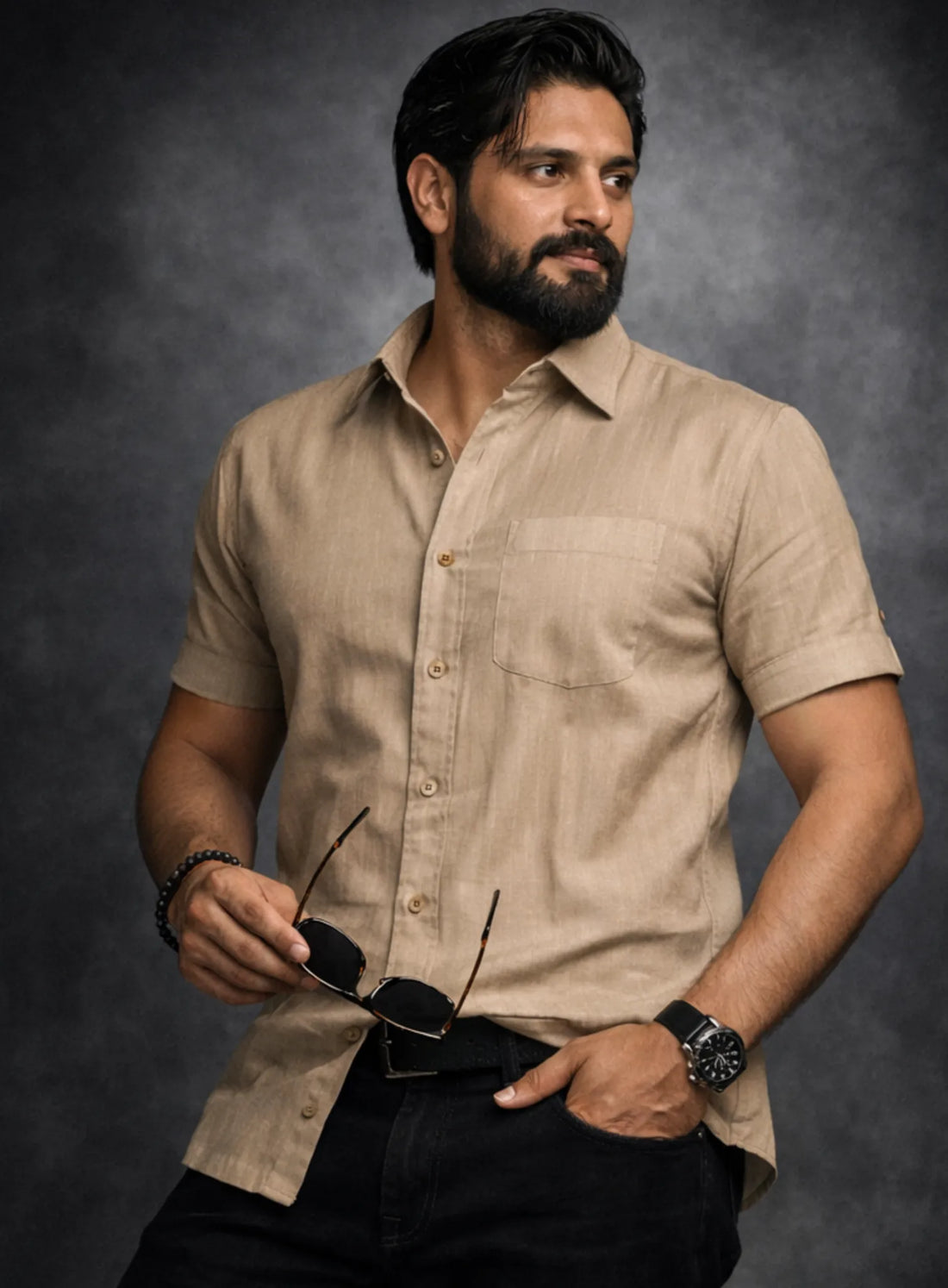 Man wearing a beige shirt and black pants with a dark background