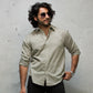 Man wearing a light olive  shirt and sunglasses against a white background