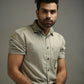 Man wearing a light olive shirt against a gray background