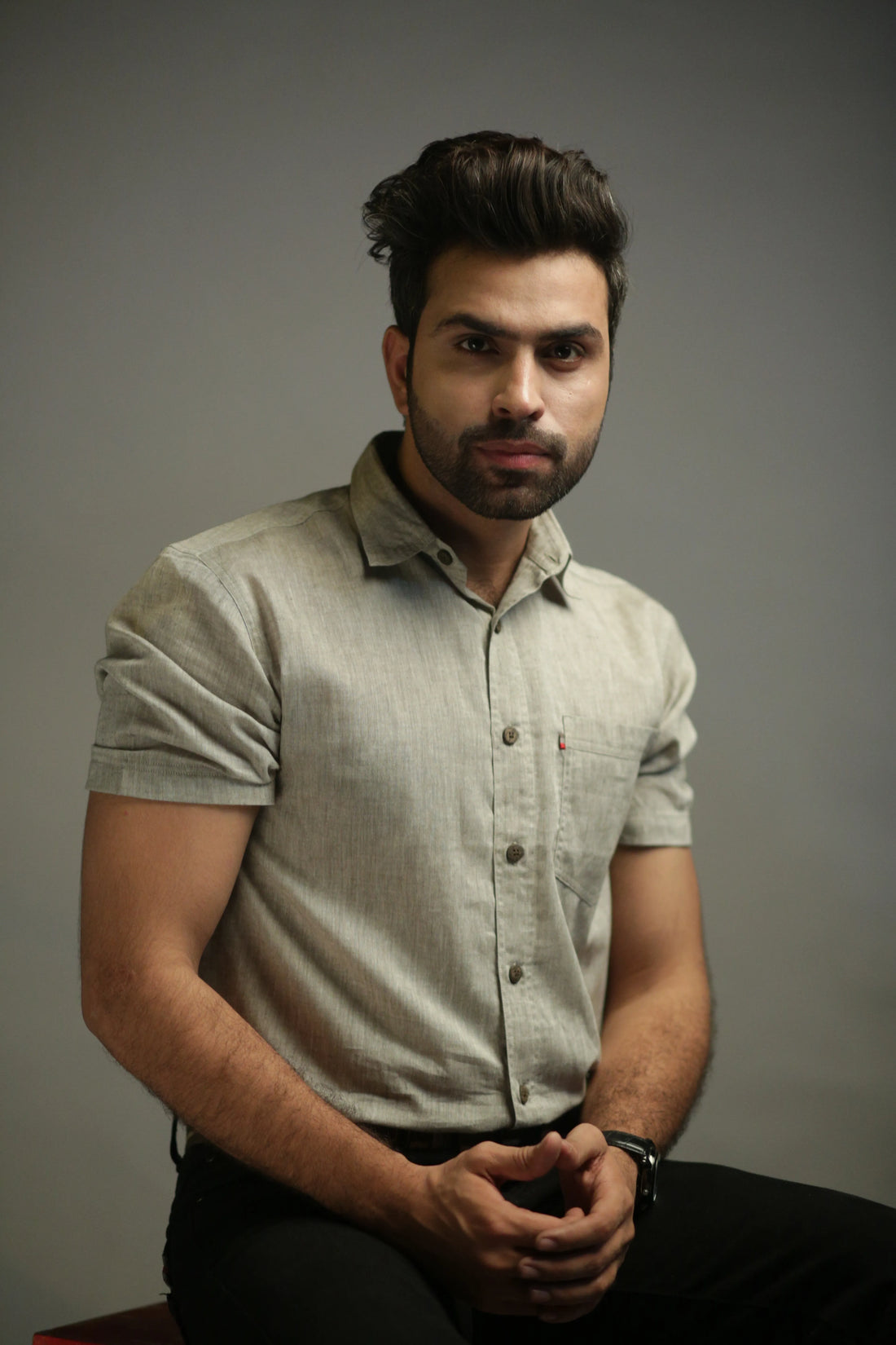 Man wearing a light olive shirt against a gray background