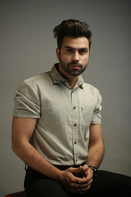 Man wearing a light olive shirt against a gray background