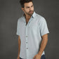 Man wearing a light gray short-sleeve shirt against a wooden background