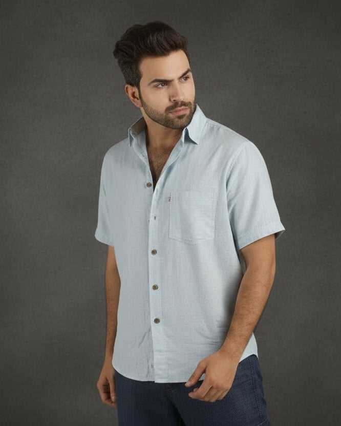 Man wearing a light gray short-sleeve shirt against a wooden background