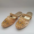 Pair of ornate gold sandals with decorative patterns on a light gray background