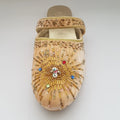 Decorative sandal with gold beading and gemstones on a light gray background