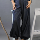 Person wearing dark blue wide-leg pants with a gray background